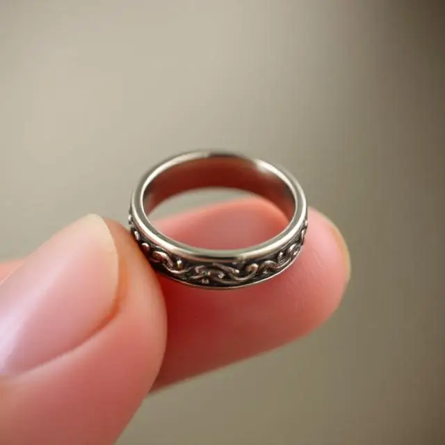 A close-up of a finished ring being held delicately in a hand.