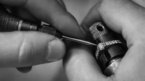 A master jeweler meticulously crafting a fine gold ring with precision tools.