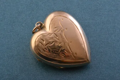 A vintage, ornate heirloom locket resting on a wooden surface, representing legacy and memory.
